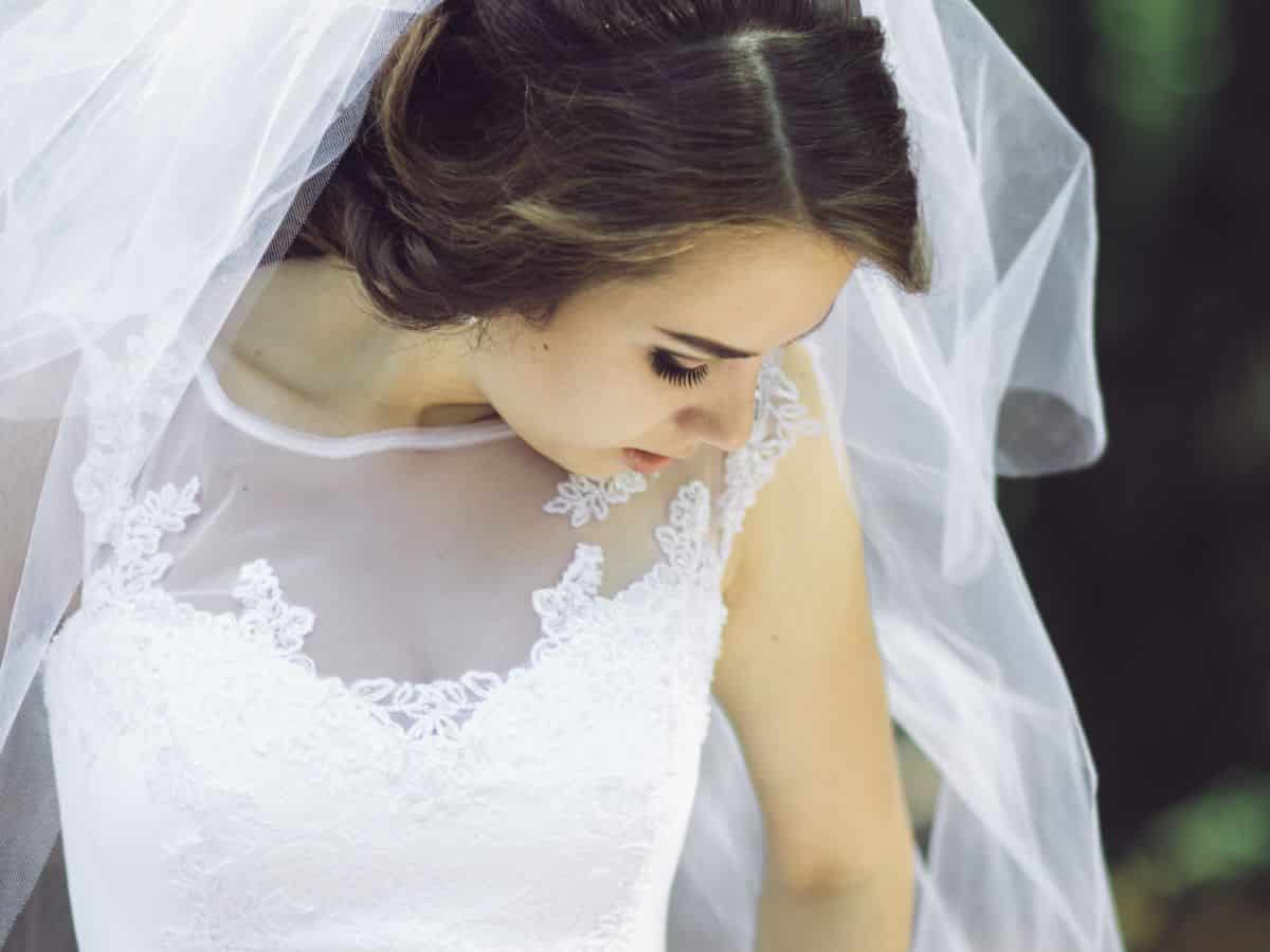 A bride in a wedding dress admiring her veil at Mall of America.