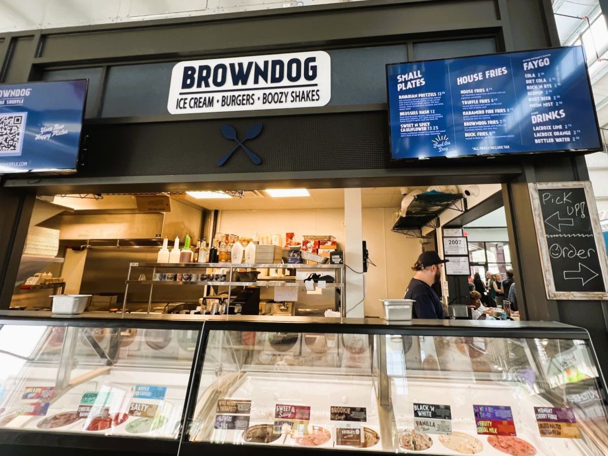Image of a restaurant counter with the sign "Browndog Ice Cream Burgers Boozy Shakes." The display case shows various ice cream flavors, and a staff member is working inside the kitchen.