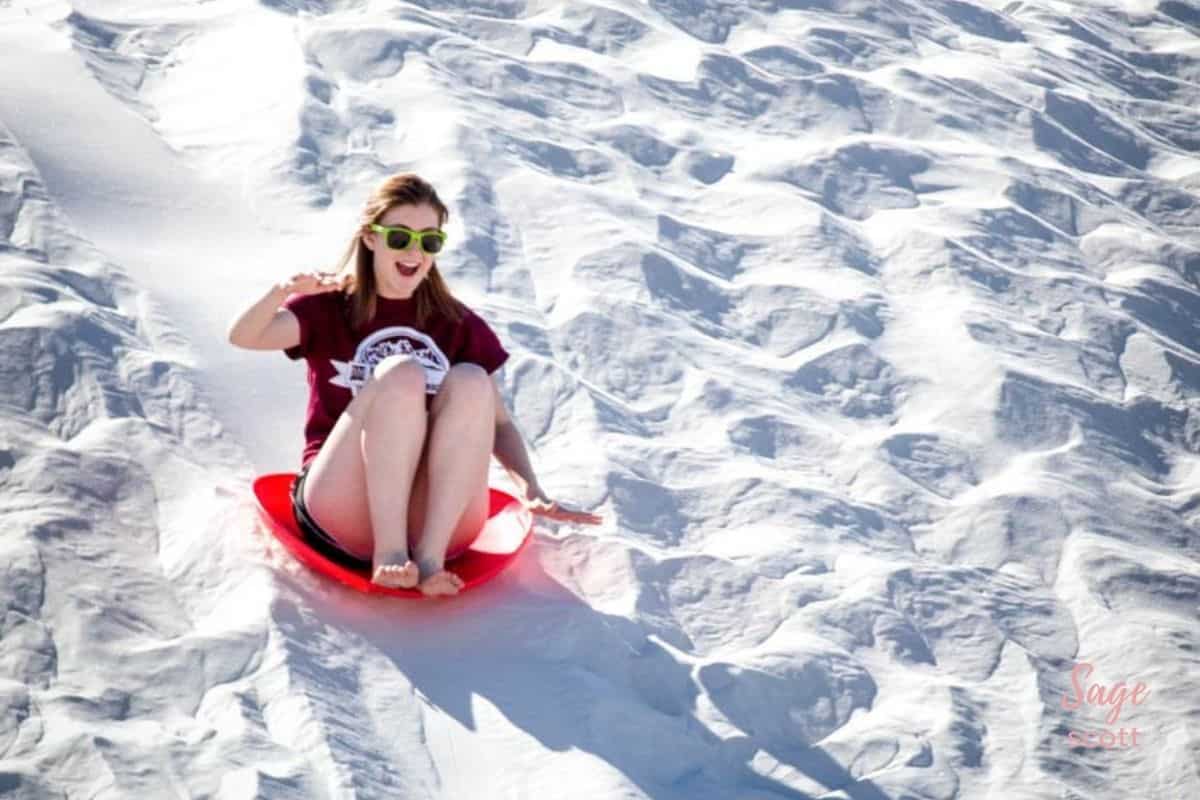Girl sliding down sand dune in White Sands New Mexico