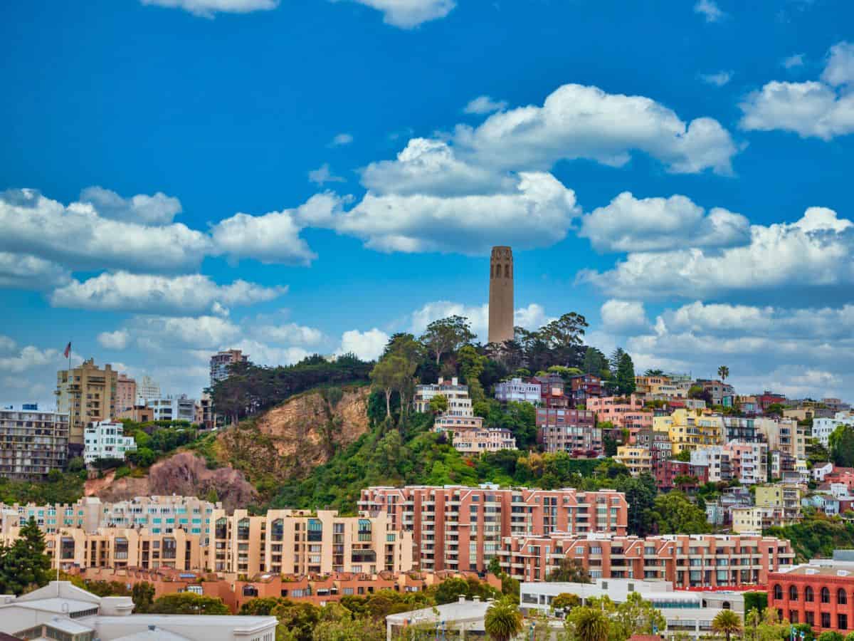 A tall white tower on top of a hill in San Francisco.