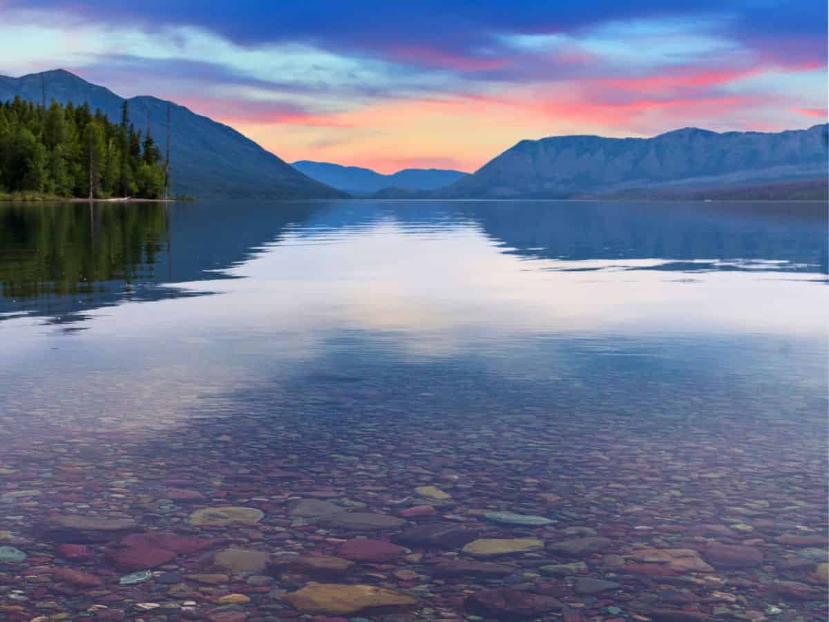 A lake surrounded by mountains and rocks at sunset.