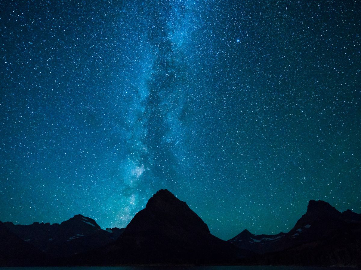 Silhouetted mountains under a star-filled night sky with the Milky Way galaxy visible in the center.