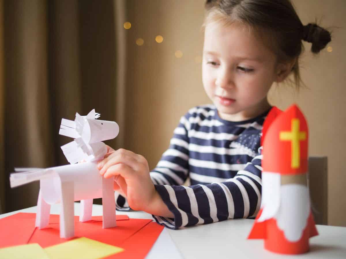 Dutch girl playing with a paper Sinterklaas and white horse.