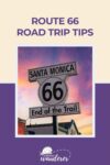 Route 66 sign in Santa Monica at sunset, reading "End of the Trail" with a purple border and travel logo.