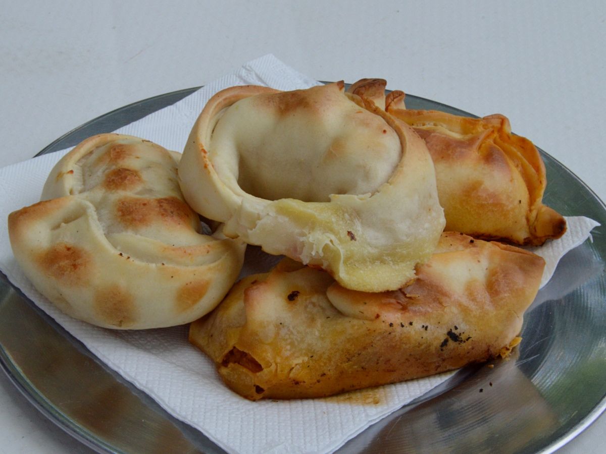 A plate with four baked empanadas on a white napkin.