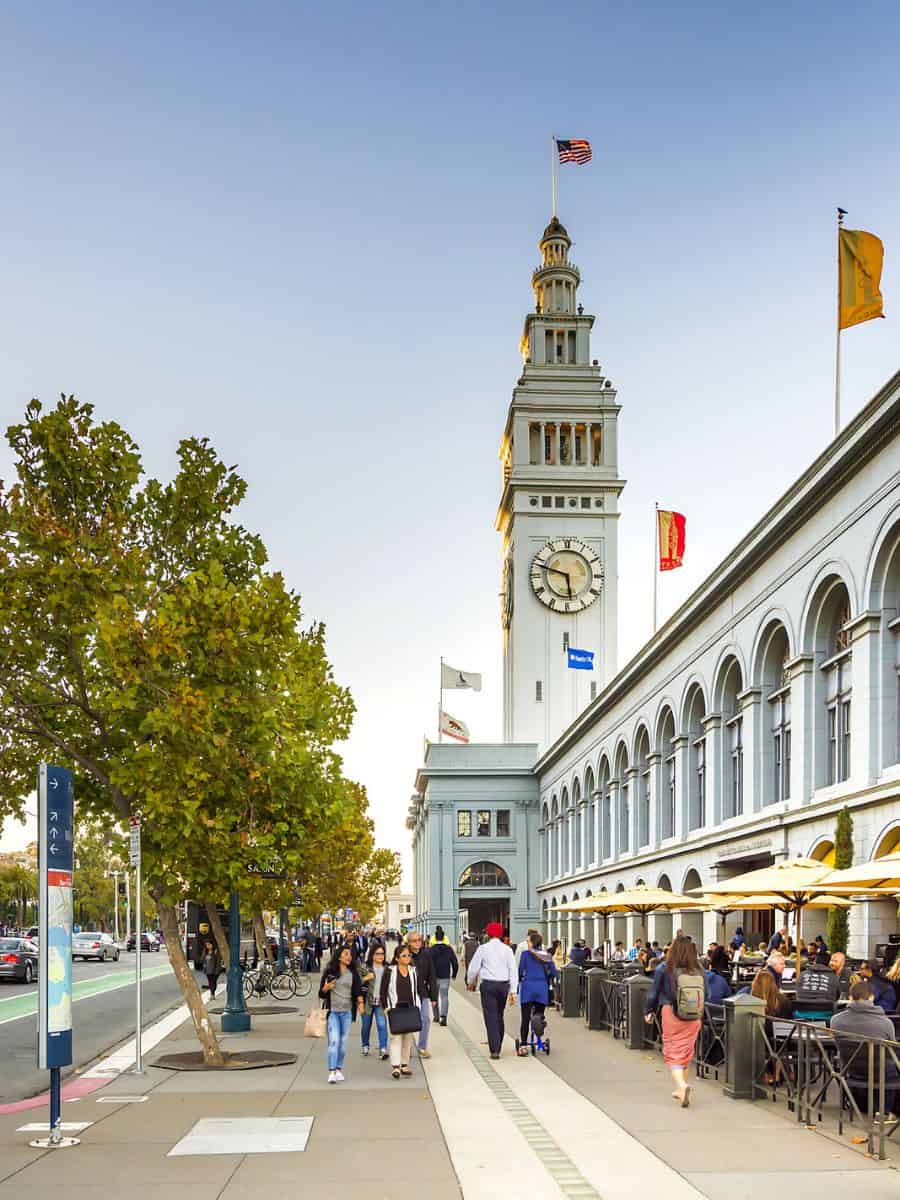 A tall tower with a clock tower along the San Francisco waterfront.
