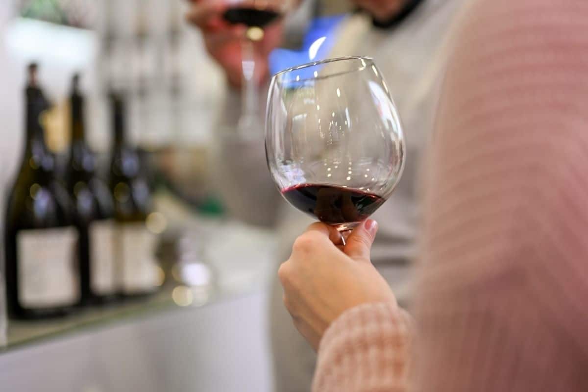 Woman tasting wine at a stainless steel bar