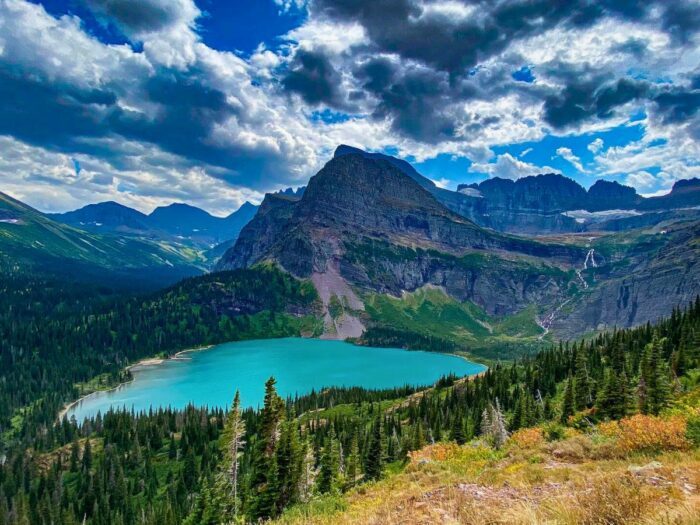 A clear lake at Glacier National Park in Montana under a cloudy sky.