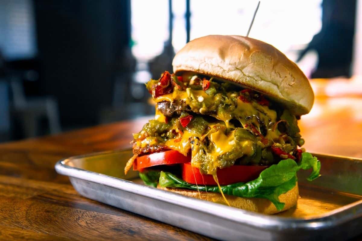A green chile cheeseburger sits on a silver tray at a Southwestern restaurant.