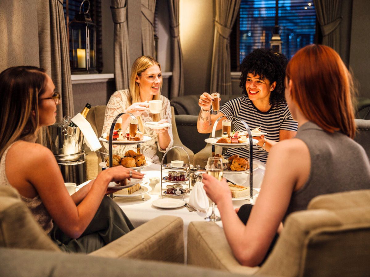 Four people enjoying afternoon tea together in a warmly lit room.