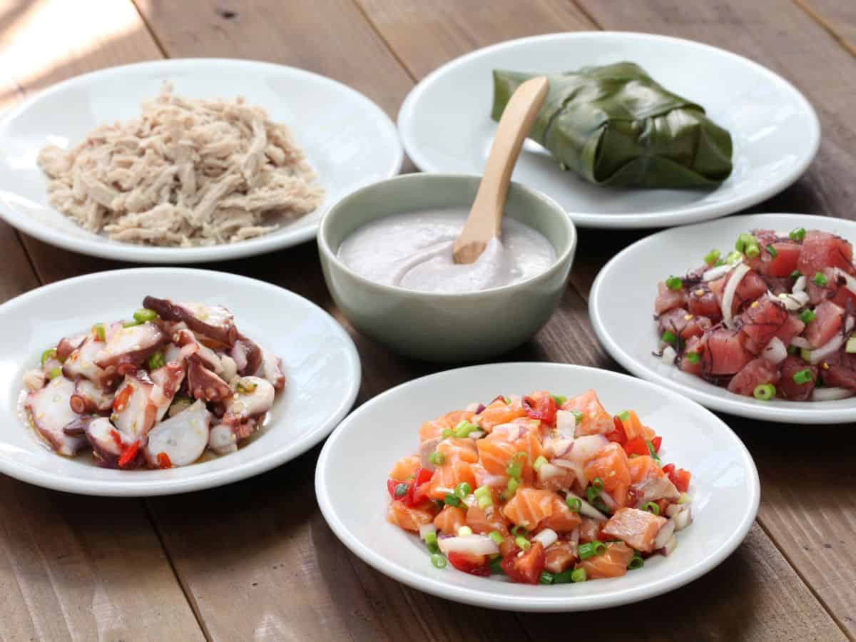 Bowls of Hawaiian luau food on a wooden table.