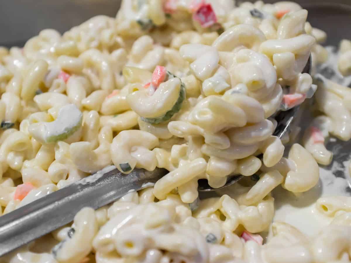 A bowl of macaroni salad with a spoon, perfect for a Hawaiian luau.