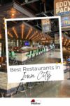 Interior of a restaurant with a bar, high green chairs, ceiling lights, and signs reading "Eddy Pack." The text "Best Restaurants in Iowa City" is displayed at the bottom.