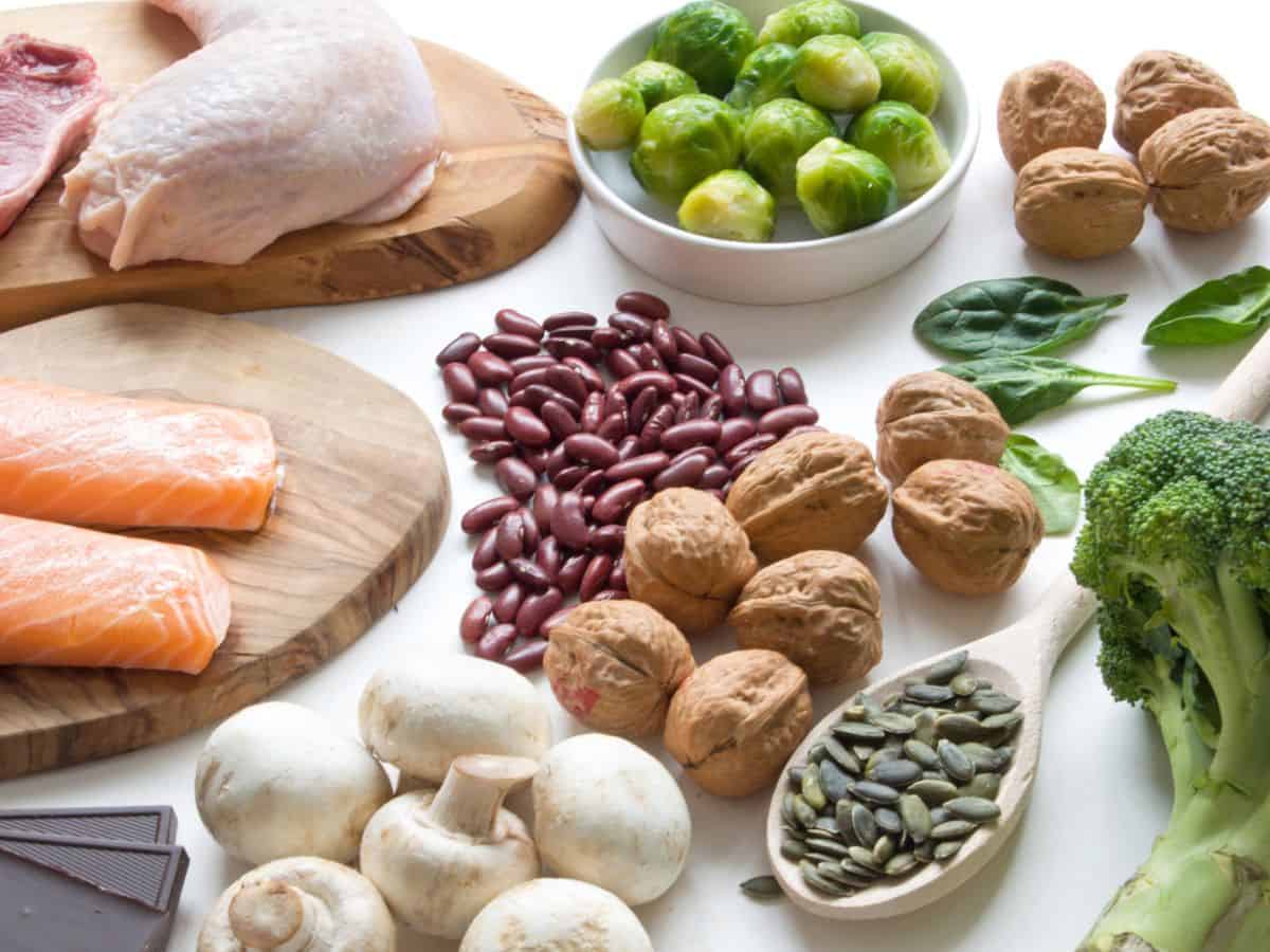 A variety of iron-rich meats, vegetables, and nuts on a cutting board.