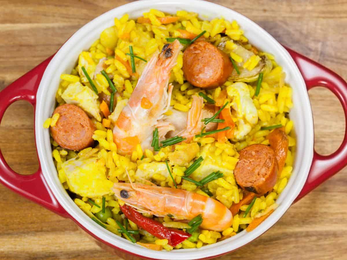 Jambalaya served in a vibrant red bowl on a rustic wooden table.