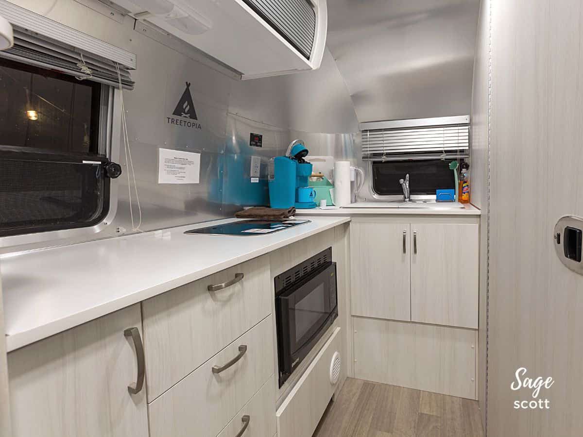 An Airstream kitchen with running water, a stovetop, and microwave.
