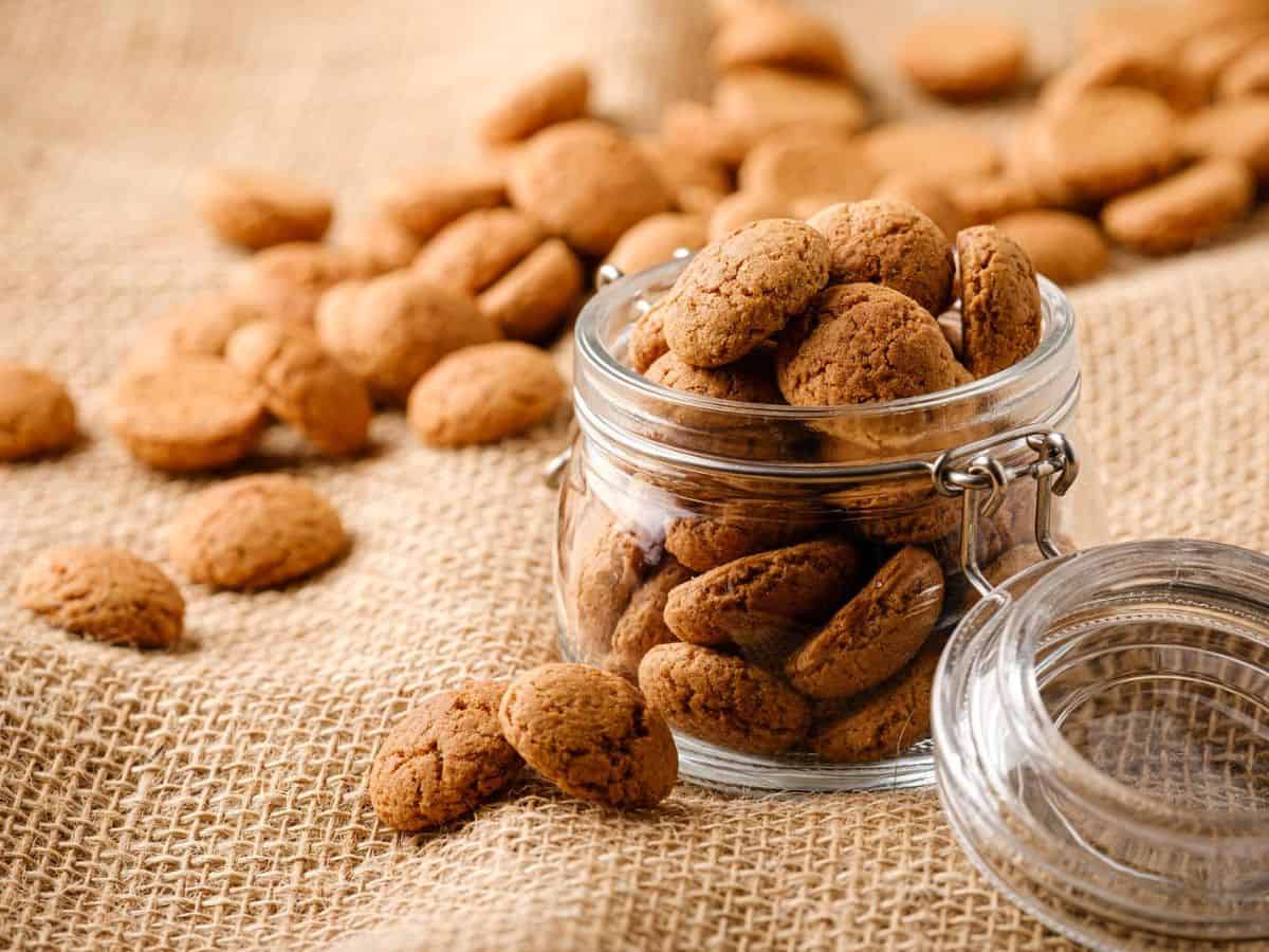 A glass jar filled with Sinterklaas cookies on a burlap cloth.