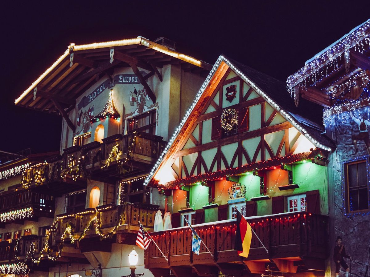 Colorfully lit, European-style buildings at night with flags and festive decorations.