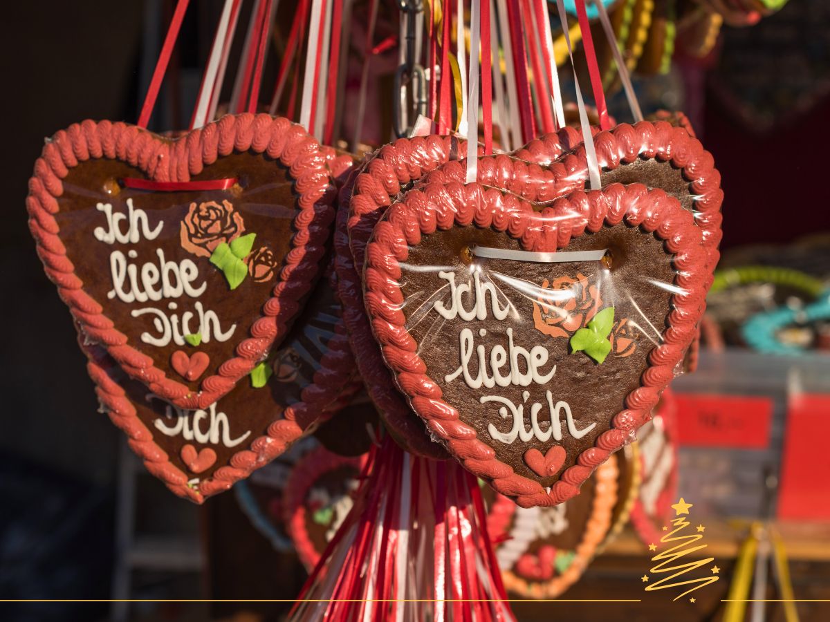 Heart-shaped gingerbread cookies with the text "Ich liebe Dich," decorated with icing and hung with ribbons.