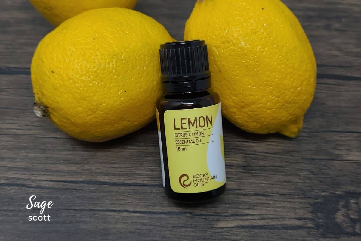 Bottle of lemon essential oil by fresh lemons