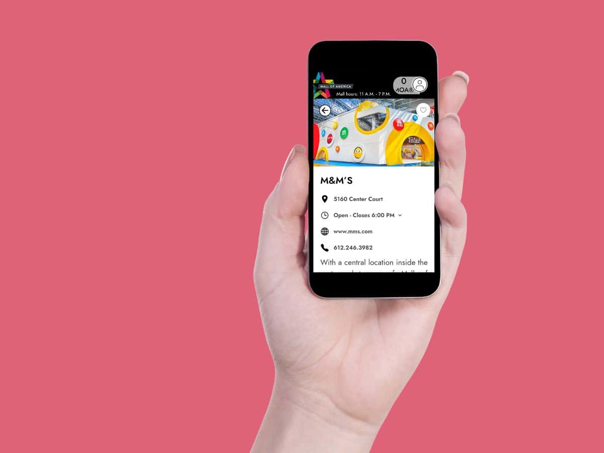 A woman holding up a phone displaying a child's app.