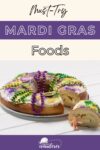 A sliced king cake decorated with purple, green, and gold icing and beads, featuring a small plastic baby figurine.