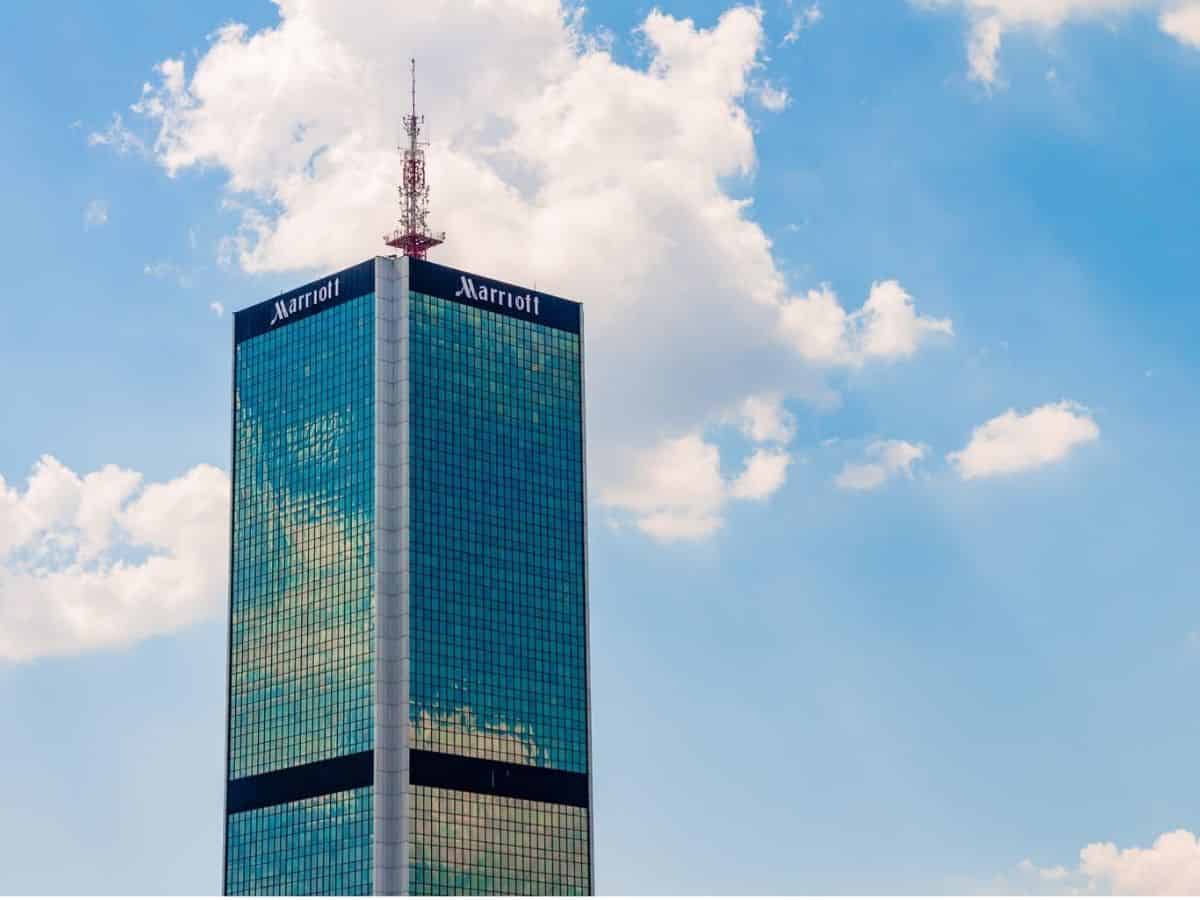 A Marriott skyscraper against a picturesque blue sky, adorned with fluffy white clouds.