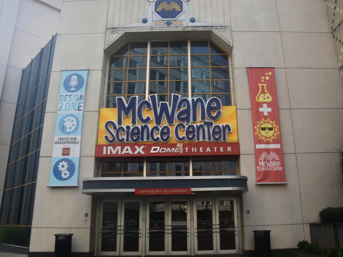 The entrance to McWane Science Center in Birmingham, Alabama, featuring the IMAX Dome Theater with banners for "Design Zone" and science-themed graphics on either side.