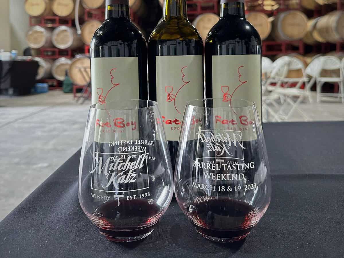 Three glasses of wine on a table next to barrels.