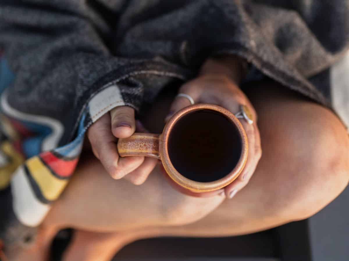 Woman holding cup of coffee in her lap - Montana Coffee Traders