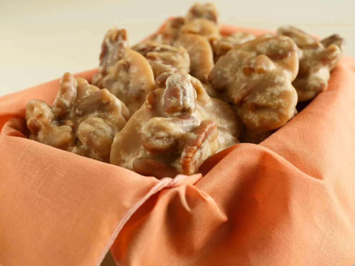 Pecan pralines in a basket with an orange napkin.