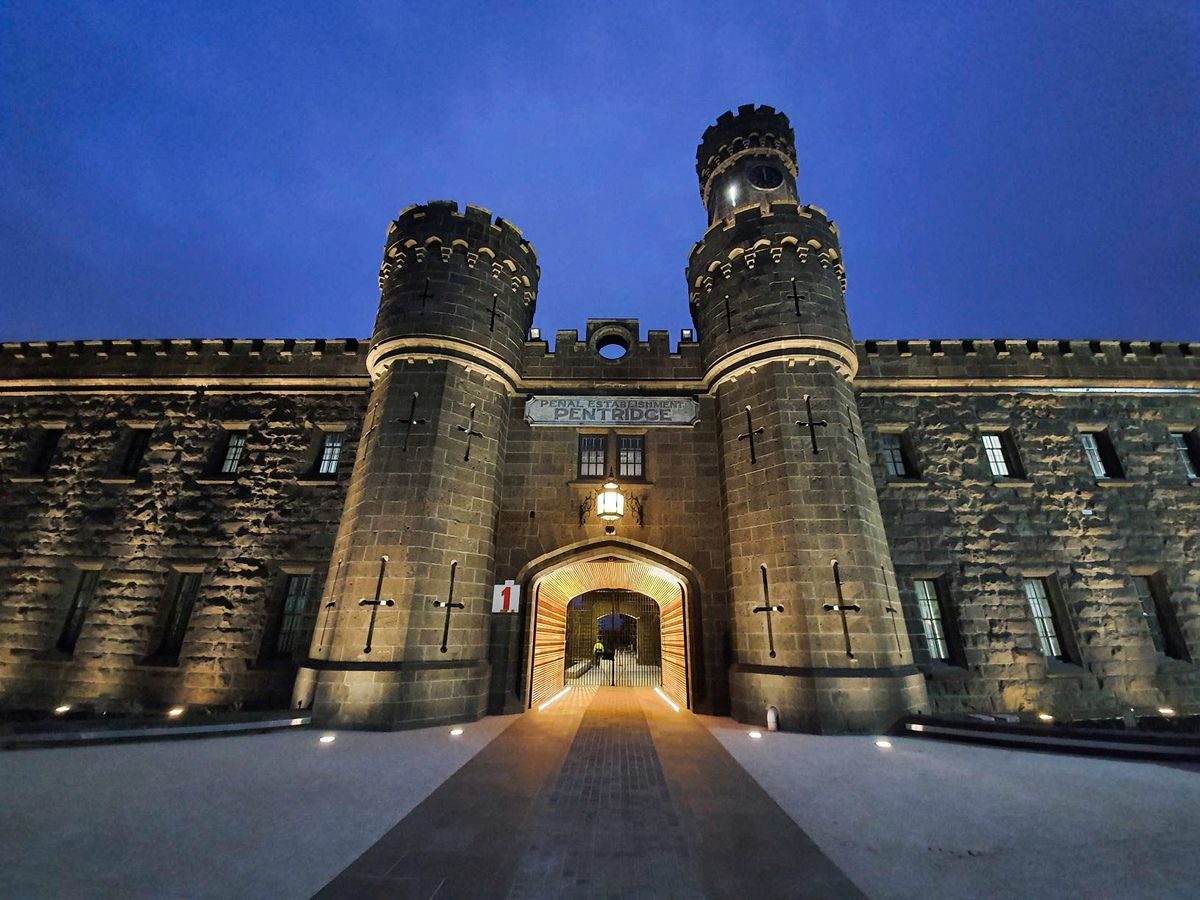 An imposing stone fortress with two cylindrical towers stands illuminated against a dusky sky, featuring an entrance archway with the name "Pentridge" displayed above.
