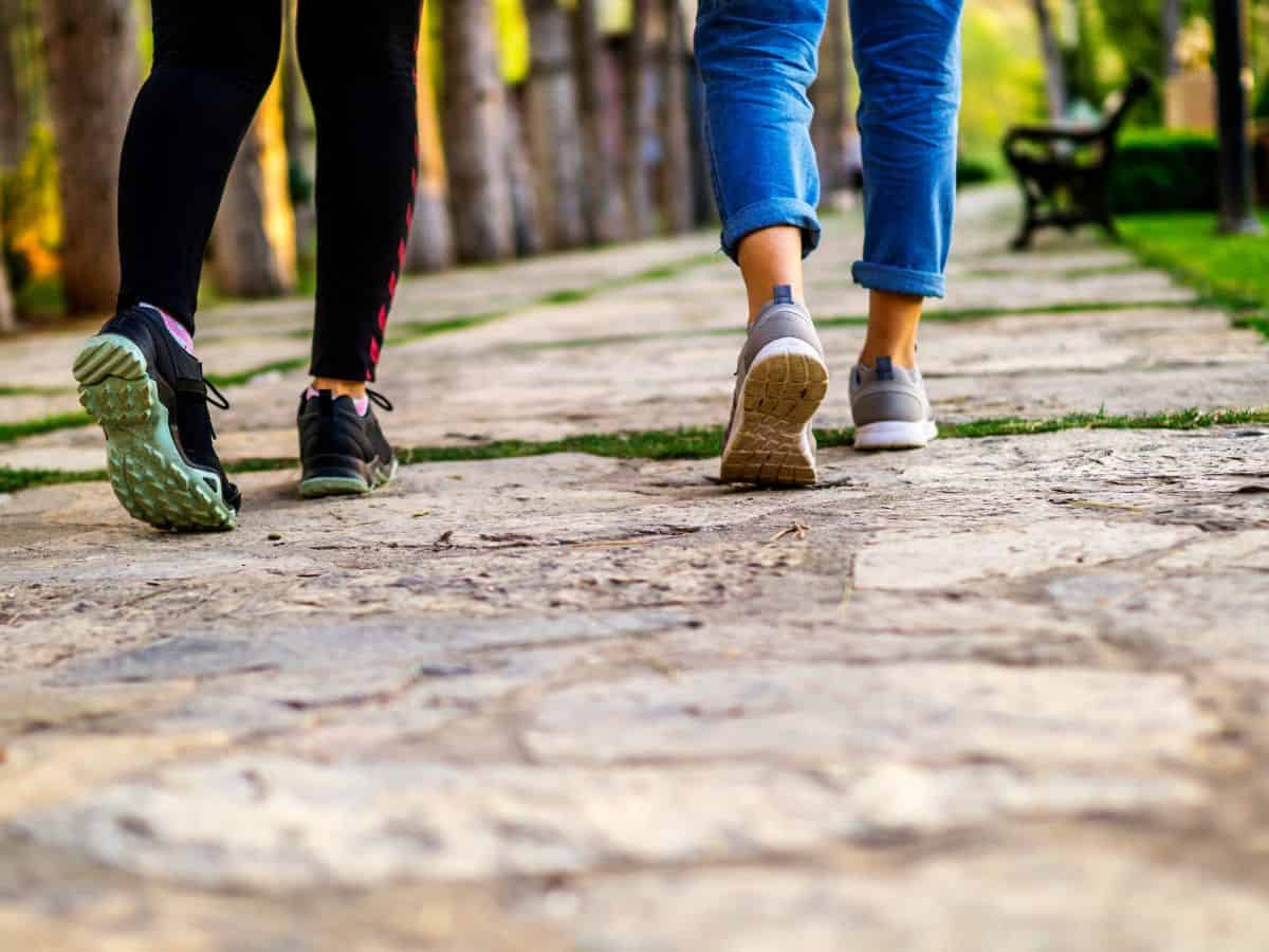 Close up of two people walking along a paved path.