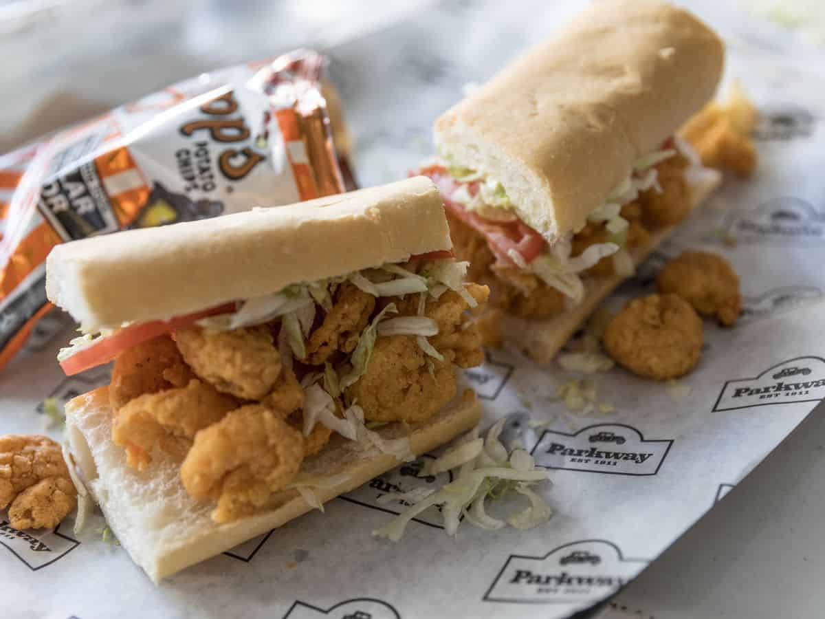 A po' boy shrimp sandwich and a bag of chips.