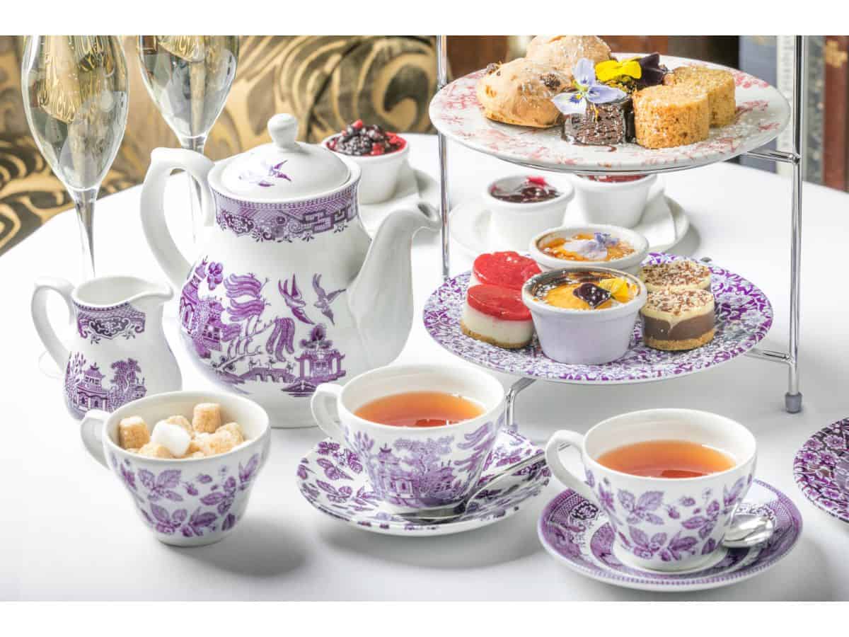 A table with tea cups and desserts.