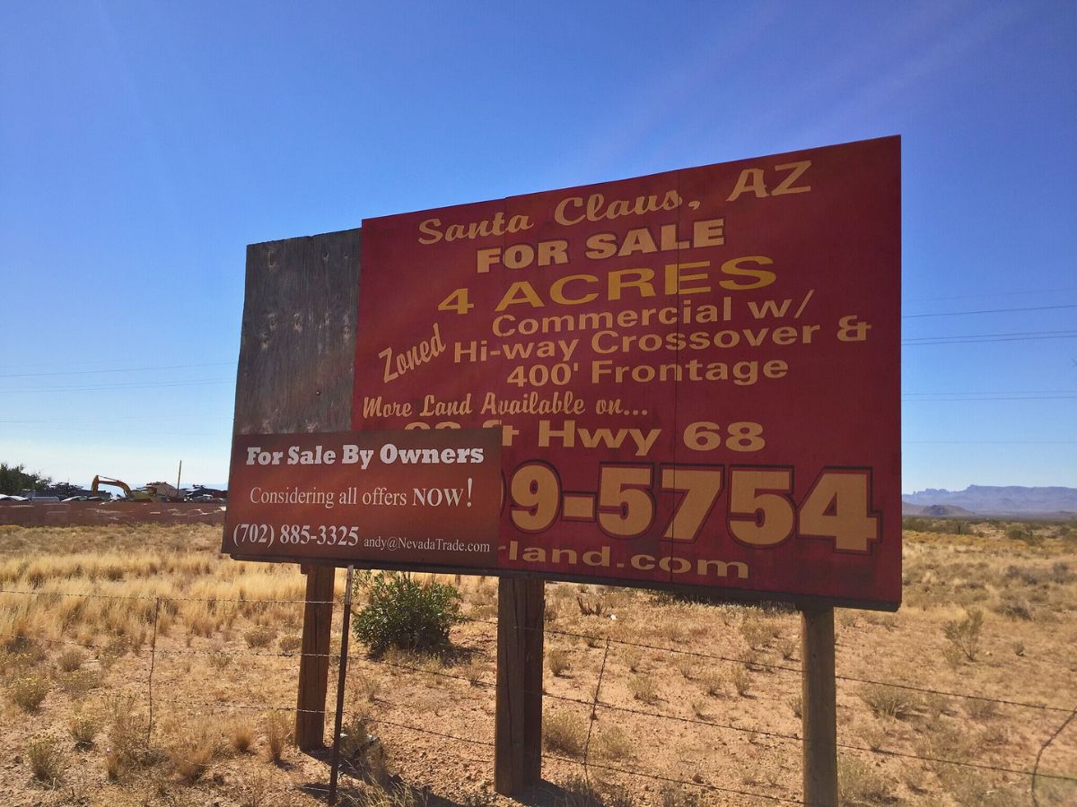 For sale sign in Santa Claus, AZ offering 4 acres of commercial land on Hwy 68 with contact information.