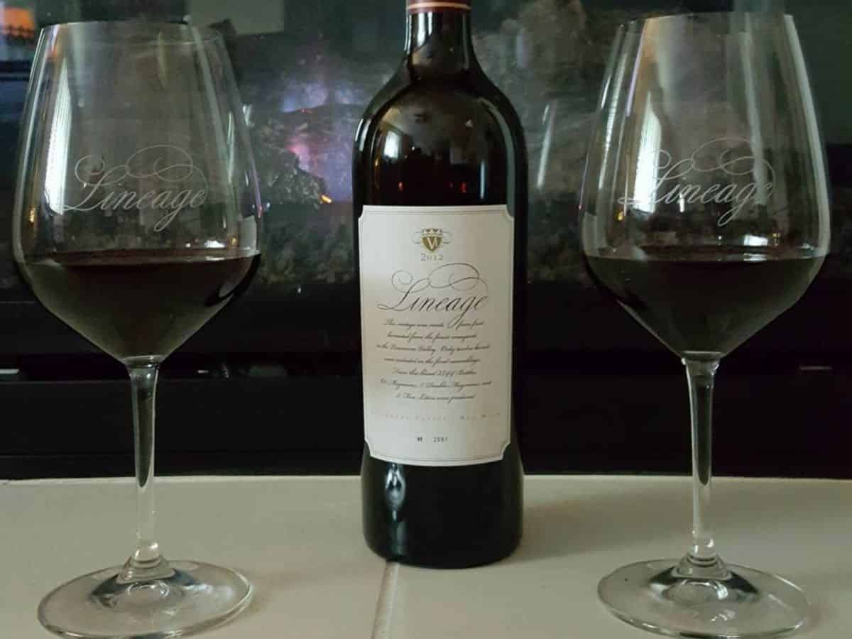 Two glasses of wine next to a bottle of wine.