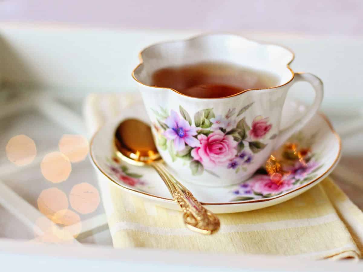 A cup of tea on a tray with a gold spoon.