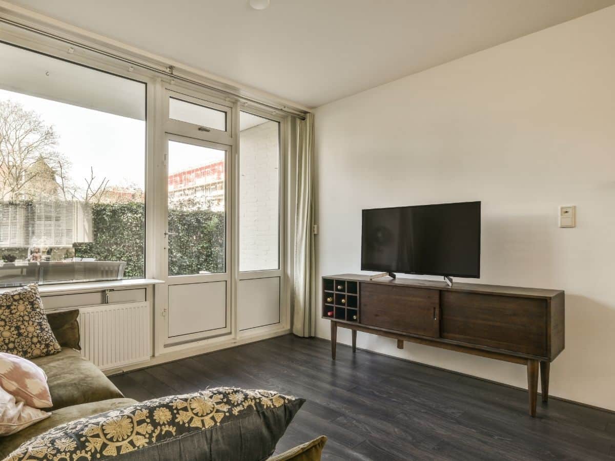 A television in a living room with large windows.