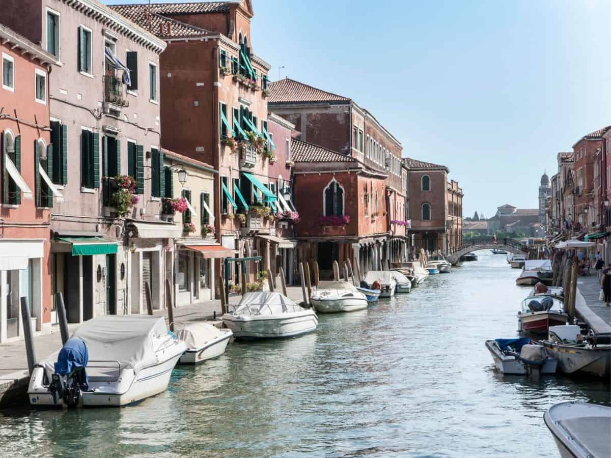 Boats docked next to colorful buildings on a beautiful canal in Murano.