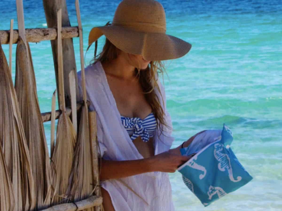 Woman putting damp swimsuit into a Wander Wet Bag