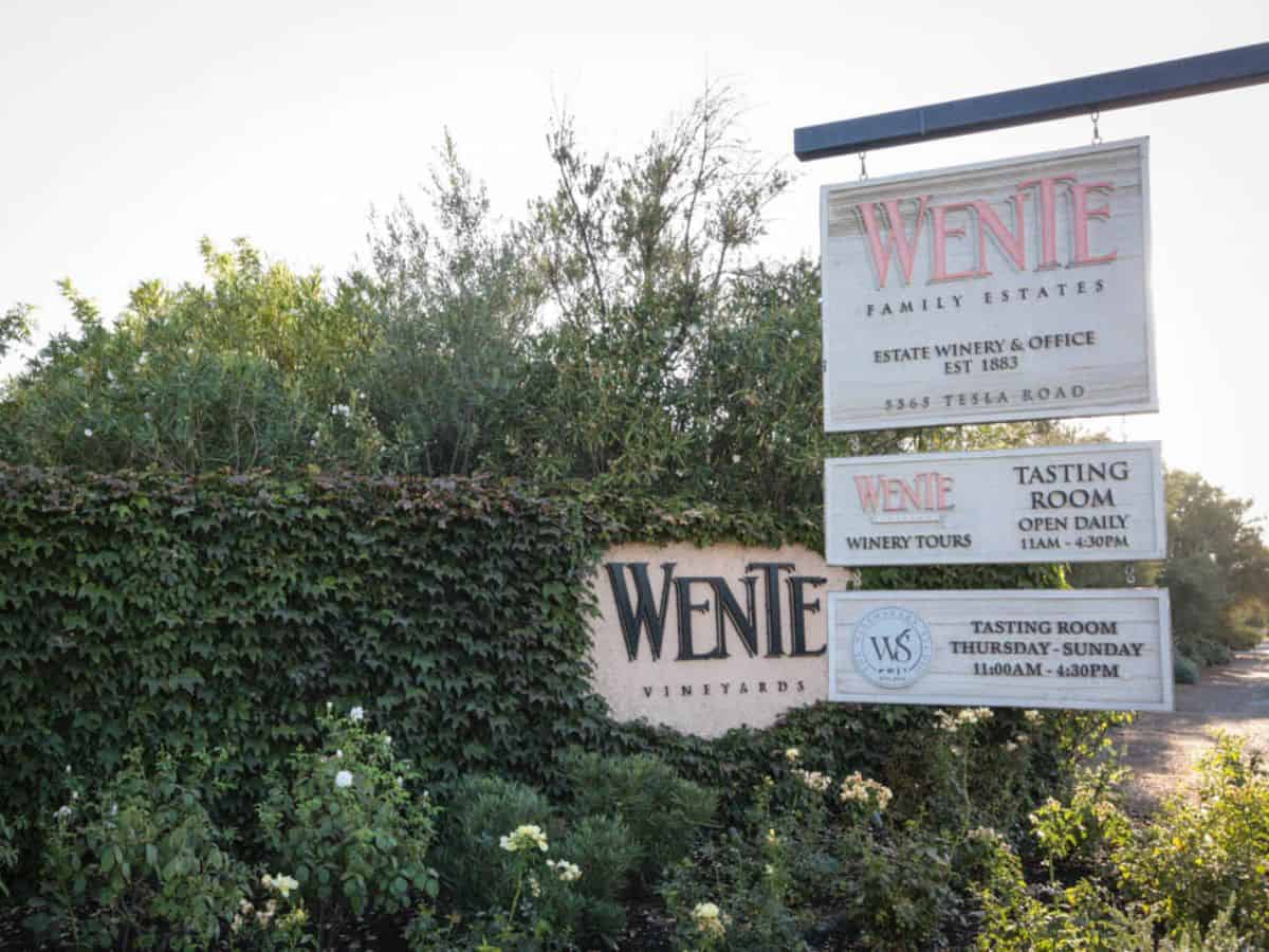 A sign for Wente in front of bushes.