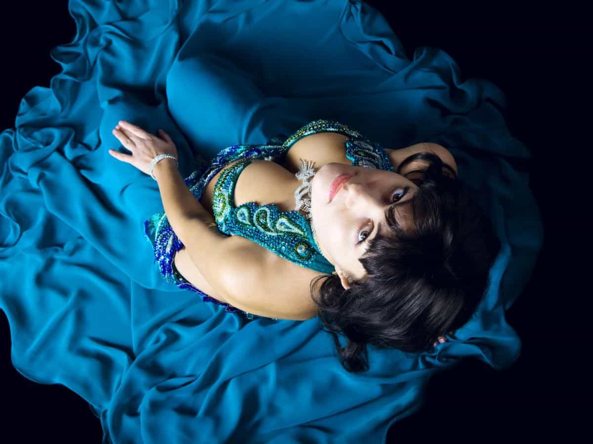 A woman in a blue Mardi Gras costume looking up at the camera.