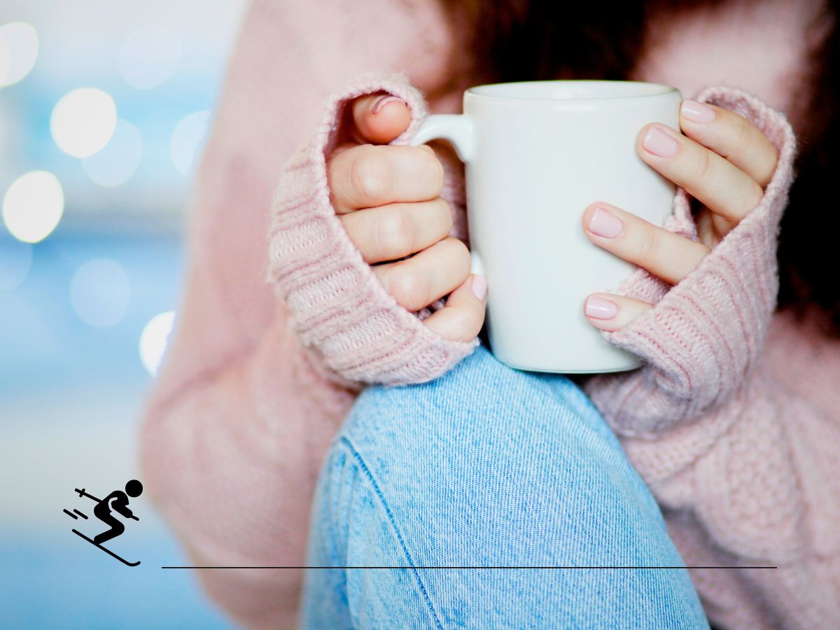 Person in a pink sweater holding a white mug, with a skiing icon overlayed on the image.