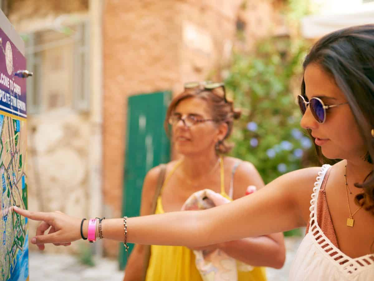 Two women participating in a scavenger hunt and pointing at a map.